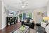 Contemporary living room with sleek black leather sofas, stylish decor, and a chic shelving unit, opening up to a spacious balcony with a refreshing view.