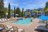 Inviting apartment complex with a sparkling outdoor pool, surrounded by sun loungers and blue umbrellas, creating a perfect oasis for relaxation.