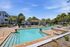 Luxurious outdoor swimming pool area with elegant lounge chairs, vibrant umbrellas, and lush palm trees, perfect for relaxation and leisure.