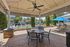 Inviting outdoor patio area with pool views, featuring seating under a stylish canopy and vibrant blue umbrellas surrounded by lush palm trees.