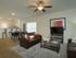 The Station at Alafaya, interior, living room, wood floor, leather sofa, dark, coffee table, tv and stand, wall art, chess set, dining room kitchen, black table for four. large window, breakfast bar seating for four, tan cabinets, stainless