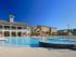 The Station at Alafaya, exterior, two level clubhouse with balcony, sparkling blue swimming pool, yellow house, tan and gray houses, lounge chairs