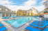 Inviting apartment community pool surrounded by comfortable blue loungers, perfect for relaxation and enjoying sunny days.