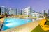 Luxurious apartment complex with a shimmering pool surrounded by modern architecture and vibrant lounge chairs, perfect for relaxation and leisure.