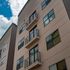 Contemporary apartment building exterior with sleek balconies and large windows under a vibrant blue sky.