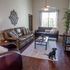 Cozy and stylish living room with plush leather sofas, natural light, elegant decor, and a welcoming atmosphere featuring a cute dog.