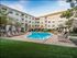 Inviting apartment complex courtyard featuring a pristine swimming pool surrounded by lush landscaping and comfortable lounge chairs.