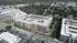 Aerial view of a modern apartment complex with a rooftop pool and lush greenery, perfectly situated in a vibrant urban setting.