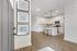 Inviting apartment entrance leading to a modern kitchen with sleek white cabinets, elegant countertops, and stylish pendant lighting.