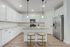 Modern kitchen with sleek white cabinets, elegant lighting, and a stylish breakfast bar for a contemporary living experience.