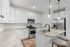 Contemporary kitchen with granite countertops, sleek white cabinetry, stainless steel appliances, and elegant pendant lighting.