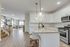 Elegant open-concept kitchen and living area with modern white cabinetry, granite countertops, and stylish lighting. Hardwood floors lead to a cozy living space, perfect for entertaining.