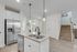 Modern kitchen featuring a sleek granite island and stainless steel appliances, enhanced by stylish pendant lighting and a light wood floor.