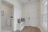 Charming entryway with elegant wooden flooring, cozy built-in bench with stylish cushions, and a modern laundry room visible through an open door.