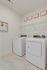 Modern laundry room with sleek washer and dryer, stylish wall art, and an elegant shelving unit.