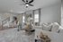 Inviting open-concept living room with modern gray and white decor, stylish ceiling fan, and plush seating creating a warm, cozy atmosphere.