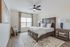 Elegant bedroom with a cozy wooden bed, plush white linens, and stylish decor, complemented by natural light from a large window.