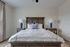 Elegant bedroom with a cozy wooden bed, plush white linens, and stylish blue accent lamps creating a serene and inviting atmosphere.