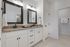 Elegant bathroom with dual mirrors, granite countertops, stylish fixtures, and modern lighting.