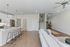 Inviting open-plan living space with a sleek kitchen island, modern bar stools, and elegant hardwood floors, leading to a cozy staircase.