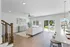 Bright and modern open-concept living room with sleek hardwood floors, cozy seating, and a large sliding glass door leading to a lush garden view.