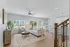 Bright and airy living room with modern decor, ample natural light, and an open-concept layout leading to a sleek kitchen and dining area.