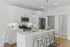 Modern kitchen with sleek white cabinetry, stainless steel appliances, and a spacious island with stylish barstool seating.