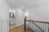 Bright hallway featuring elegant wooden stairs, leading to a modern bathroom with stylish fixtures and a glimpse of a cozy bedroom.