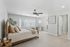 Inviting bedroom with plush carpeting, a cozy bed adorned with soft neutral linens, and ample natural light streaming through large windows.