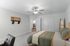 Inviting bedroom with a plush green bedspread, modern ceiling fan, and tasteful wall decor, exuding a serene and stylish ambiance.