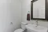Elegant bathroom with sleek fixtures, featuring a pristine white sink, modern faucet, and a large decorative mirror. A tasteful touch with a brown towel and soap dispenser enhances the sophisticated look.