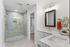 Luxurious bathroom featuring a modern glass shower, dual sinks, sleek mirror, and elegant finishes.