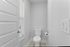 Bright and modern bathroom corner featuring a sleek toilet and window with blinds, offering a clean and inviting atmosphere.