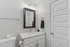 Sleek and modern bathroom with elegant mirror, chic lighting, and ample counter space, exuding sophistication.