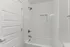 Modern bathroom featuring a sleek white bathtub, elegant subway tile walls, and polished chrome fixtures.