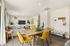 Bright and inviting living area with modern decor, featuring vibrant yellow chairs, a sleek dining table, and a comfy sofa, perfect for stylish living.