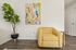 Chic living space with a cozy yellow armchair, vibrant artwork, and lush indoor plant, perfect for relaxation.