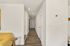 Inviting hallway with modern design, sleek hardwood floors, and crisp white walls leading to a chic, contemporary apartment interior.