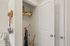 Efficient storage closet with cleaning tools and organized shelves in a modern apartment.