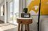 Bright living space with sliding glass doors, stylish side table adorned with vintage radio and plant, complemented by modern art and cozy ambiance.