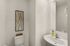 Elegant bathroom featuring modern fixtures, sleek white sink, and minimalist wall art.