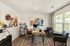 Bright and modern home office featuring elegant wood flooring, large window for natural light, stylish artwork, and comfortable seating area.