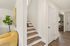 Inviting entryway with sleek wooden stairs, modern decor, and warm natural lighting in a stylish apartment.