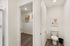 Modern bathroom with sleek design featuring a walk-in closet and elegant wall art. Warm wood flooring adds sophistication.