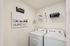 Bright and functional laundry room featuring modern washer and dryer, complemented by elegant wall art and organized shelving.