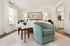 Inviting bedroom with elegant decor featuring a cozy bed, modern teal armchair, and bright natural light.