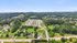 Scenic aerial view of a vibrant residential community nestled among lush greenery, with rolling hills in the background and easy access to major roadways.