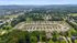 Expansive aerial view of a picturesque residential community nestled in lush greenery, showcasing beautifully designed homes and scenic surroundings.
