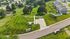 Scenic aerial view of a landscaped residential area featuring green lawns, paved driveways, and charming suburban homes surrounded by lush trees.