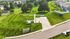 Aerial view of a beautifully landscaped green space with well-maintained lawns, modern pathways, and charming neighborhood houses surrounded by lush trees.